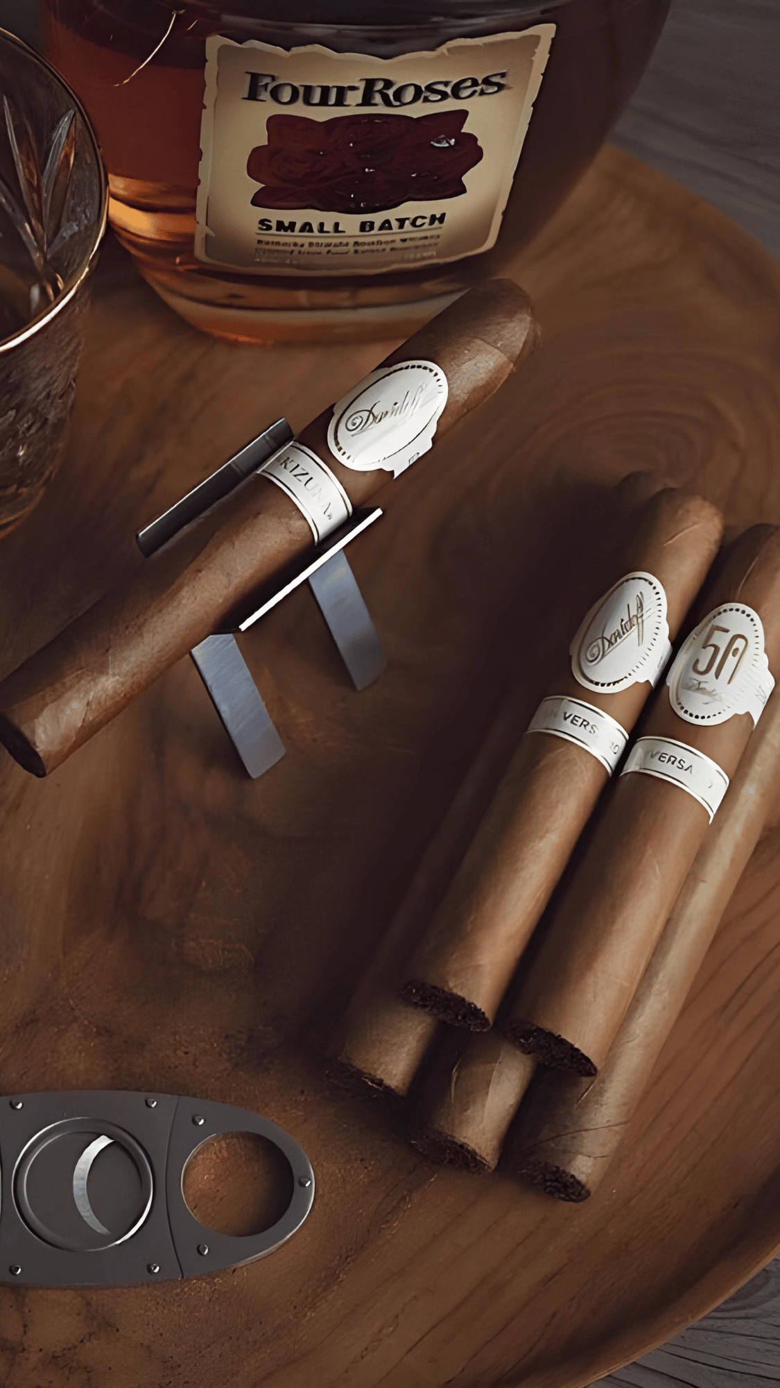 Close-up of cigars and cutter by a bottle — ritual tools with quiet presence