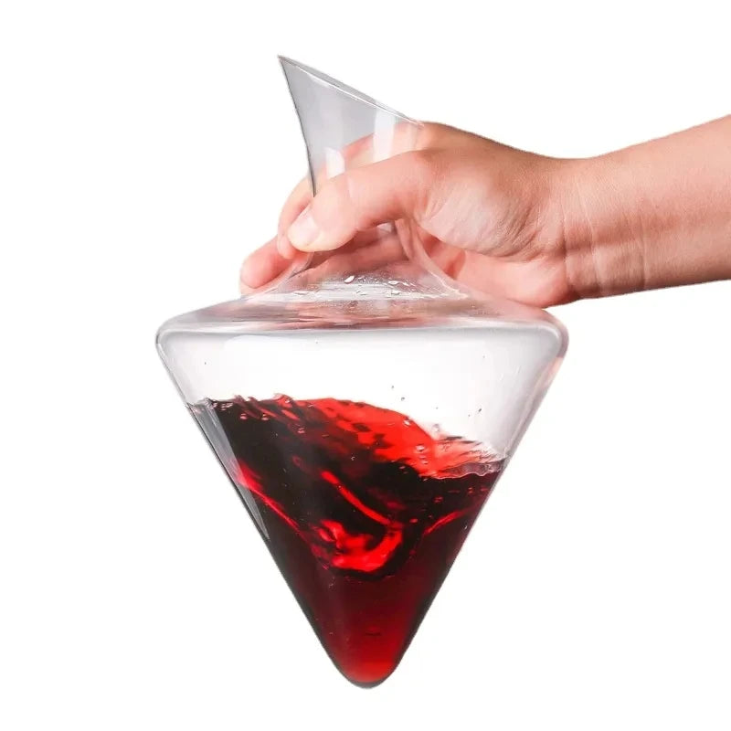 Hand holding conical wine decanter while red wine swirls inside transparent crystal body