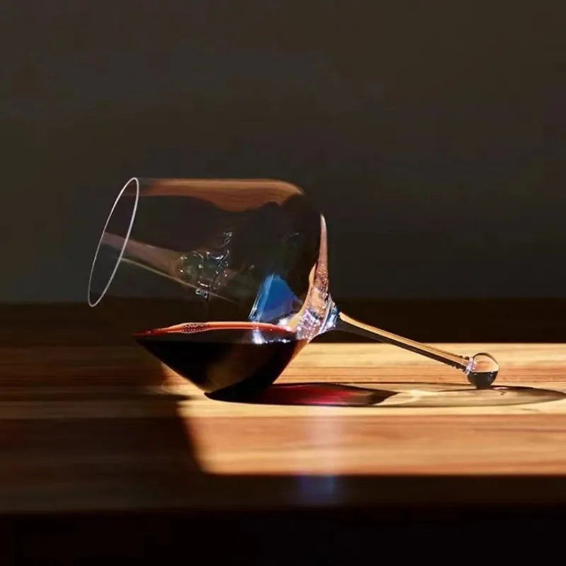 large bowl red wine glass with droplet base held by a man near fireplace