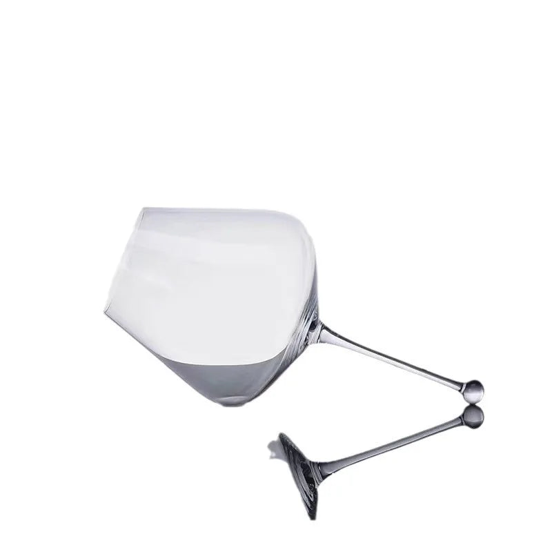 modern gravity wine glass on wooden table catching warm light