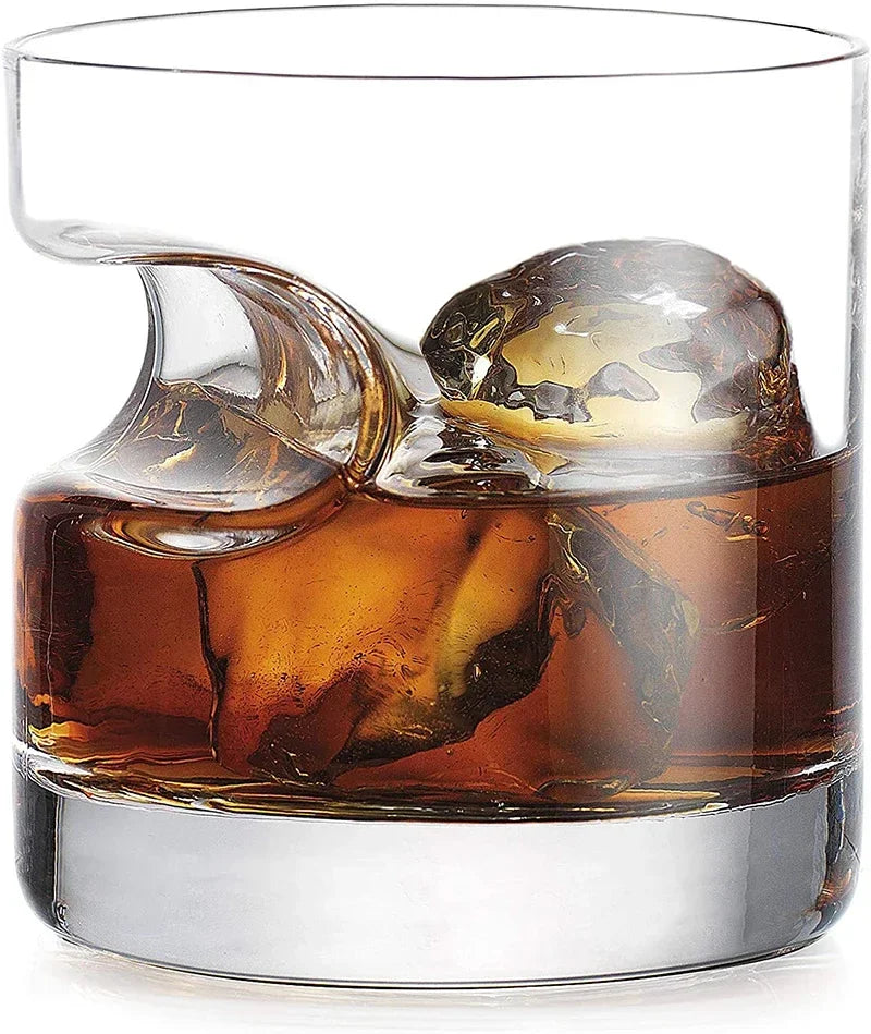 Whiskey tumbler with cigar notch in lounge setting with decanter