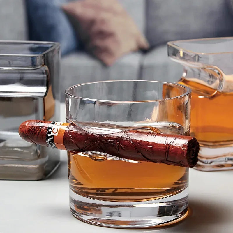 Square whiskey glass supporting cigar above ice cubes