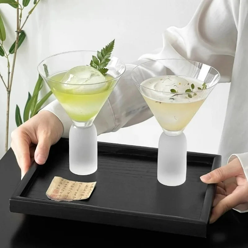 side view of tall cocktail glass on stone pedestal against dark background