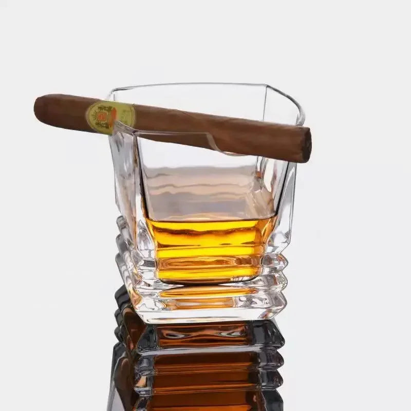 Hand holding whiskey and cigar glass during poker night