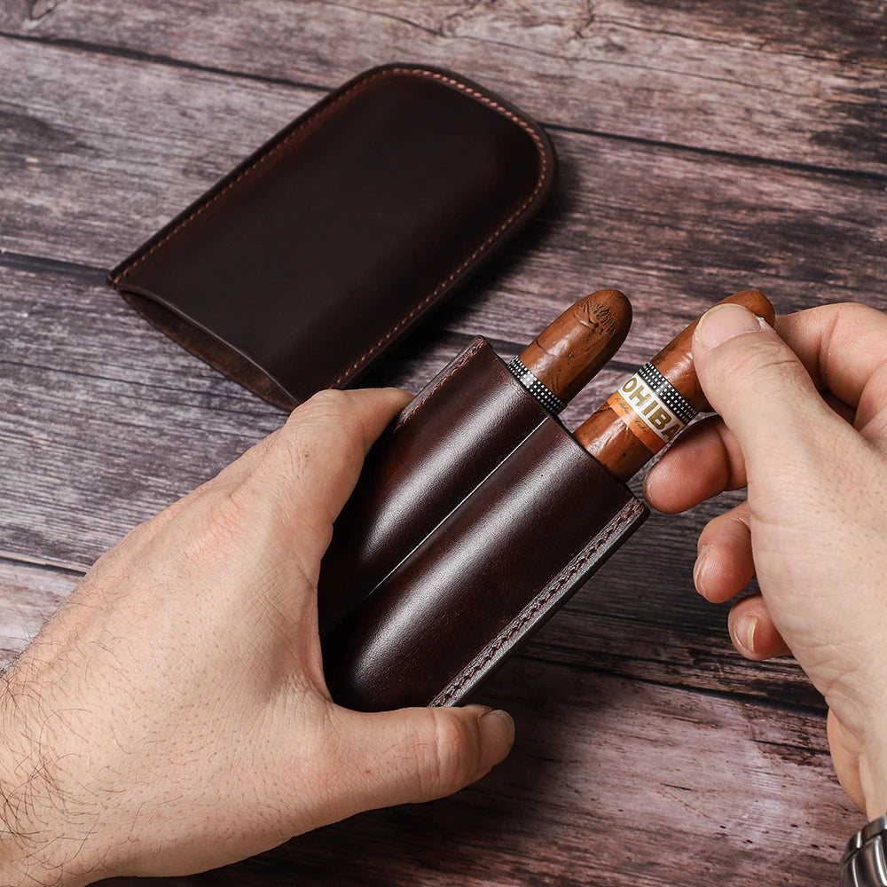 leather cigar case holding three cigars on wooden table